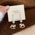Gold-tone rocking horse drop earrings with delicate pearls on a display card holder - Golden Rocking Horse Ear Hooks (MMW40)