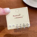 Set of six silver-toned earrings including zircon studs, small hoops, and sparkling crosses. - Silver Cross Style (EKT018)