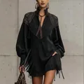 Gros plan d'une robe noire élégante avec broderie aux épaules et longues franges - XS / Robes / Noir