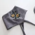Detailed view of elegant floral bead embroidery on a gray knitted winter headband. - Beaded Scarf