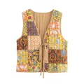 Detailweergave van een omkeerbaar gewatteerd vest met bloemenpatchwork en striksluiting. - S / Tops / Geel Bloemen