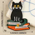 Toppa ricamata gatto nero su libri, patch termoadesiva 7.1x5.5cm per abbigliamento DIY. - Gatto su Pila di Libri / 7.1x5.5cm