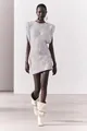 Vista dettagliata di un mini abito argentato con paillettes, senza maniche e spalline - Bianco