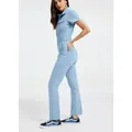 Vue latérale d'un mannequin en combinaison en jean bleu clair avec baskets. - Bleu clair