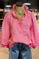 Detailed view of pink V-neck blouse with floral embroidery and ruffle puff sleeves - Pink