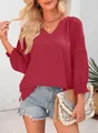 Modell mit roter V-Ausschnitt-Bluse mit eleganten Faltenärmeln und Häkeldetails. - Dunkelrot