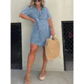 Détail d'une robe chemise en jean bleu avec un ourlet à franges et des manches courtes - Bleu