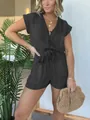 Front view of a 2024 short sleeve tencel denim romper on a model with straw bag - S / Set / Black