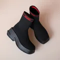 Macro detail of breathable black fly-knit sock boots featuring a chunky platform rubber sole - 35 / Black And Red