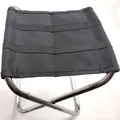 Detalle de cerca de un taburete de camping plegable negro portátil con tela de asiento - Plateado