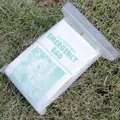 Macro view of the silver emergency sleeping bag inside a clear weatherproof plastic bag. - Yellow Edge Style