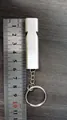 Silver high-frequency aluminum survival whistle keychain shown with measuring ruler for size - Silver