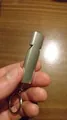 Macro view of a silver double-tube aluminum emergency survival whistle with keyring - Gold
