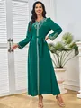 Elegante groene maxi-jurk met lange mouwen, goud borduurwerk en een strikceintuur in de taille - S / Dresses / Donkergroen