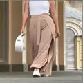 Elegant beige belted wide-leg culottes worn by model walking in outdoor setting - XS / Bottoms / Apricot