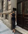 Détail d'une élégante robe longue en maille ajourée noire dans un contexte urbain - S / Robe Sans Manches / Noir