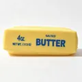 Gros plan détaillé d'un jouet squishy en forme de bâton de beurre jaune imprimé. - Bâton de Beurre à la Farine (14cm)