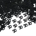 Close-up view of black number 50 confetti for 50th birthday party table decoration - 15g/Pack / Black