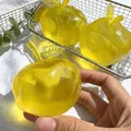 Jouet anti-stress spongieux jaune translucide en forme de pomme tenu dans la main - Pomme / Jaune