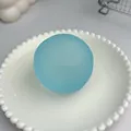 Primo piano di una palla antistress blu opaco posata su un piatto decorativo bianco. - Blu Opaco