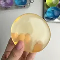 Bola antiestrés amarilla moldeable con una textura de gelatina translúcida en mano - Amarillo Alta Transparencia
