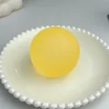 Pallina antistress gialla smerigliata fatta a mano su un piatto bianco decorato a mano. - Giallo opaco