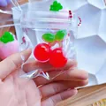 Close-up of a red mini cherry-shaped TPR squishy toy inside a clear zipper bag - Mini Cherry / PVC Bag + Chain
