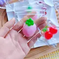 Close-up of pink strawberry squishy toy in a mini clear zip bag with a pink ball chain - Mini Strawberry / PVC Bag + Chain