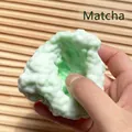Vue détaillée d'une main pressant une balle anti-stress verte matcha très moelleuse - Vert matcha / Vert