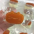 Cute cat-shaped cheese squishy stress relief toy in individual clear plastic packaging - Caramel color