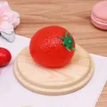 Balle anti-stress en forme de tomate rouge présentée sur un support en bois rond - Style Fraise