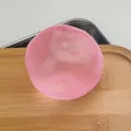 Balle anti-stress malléable rose translucide sur une planche en bois version SKU - Balle Fait Main / 6cm / Rose