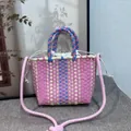 Detailed view of a colorful woven bucket bag with a pink shoulder rope strap design - Pink