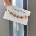 Verstelbare goudkleurige trekkoordarmband met sprankelende, met kristal ingelegde bloemen - 5 Flowers Gold Base / Goud