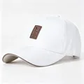 Gedetailleerde weergave van een witte honkbalpet met een bruine leren logo patch - Volwassene, Hoofdomtrek 58cm Verstelbaar / Wit