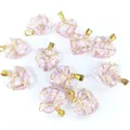 Detalle de colgantes de corazón de cristal rosa hechos a mano envueltos en hilo dorado - Rosa transparente