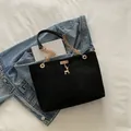 Elegant black suede tote bag with gold chain strap and deer charm on denim - Black