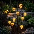 Detailed view of Halloween solar tree light with glowing skull lanterns in a garden - Skull