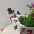 Nahaufnahme einer Schneemann-Figur, die am Rand eines weißen Blumentopfs hängt - Weihnachts-Schneemann-Stil