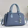 Sac à main élégant en cuir Saffiano bleu avec breloque trèfle en perles et bandoulière. - 27x13x18cm / Bleu