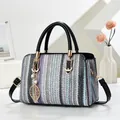 Detalle del bolso tejido a rayas con colgante de hoja dorada y asas negras - Negro