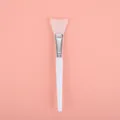 Pinceau applicateur de masque facial en silicone avec manche blanc sur fond rose - Pinceau à Masque en Spatule