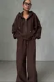 Close-up van vrouw in oversized donkerbruine hoodie met rits en wijde trainingsbroek - S / Boven- En Onderstuk / Bruin