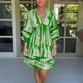 Detail view of a green V-neck printed dress with cinched waist and flared sleeves - S / Dresses / Green