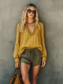 Detail of a casual yellow V-neck ruffle blouse with long sleeves and light texture. - Yellow