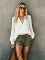 Casual white long sleeve V-neck blouse styled with olive shorts against a wall - S / Tops / White