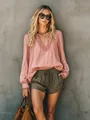 Close-up detail of a dusty pink ruffled V-neck blouse with long sleeves in a casual setting - S / Tops / Pink