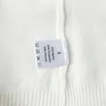 Detail shot of white knitted vest care label showing material composition and size S - S / Top And Bottom / White