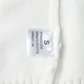 Primo piano dell'etichetta del maglione bianco con taglia S e composizione materiale - Taglia S / Top / Bianco