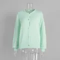 Detailansicht einer minzgrünen Strickjacke mit Silberknöpfen auf einer Schaufensterpuppe. - S / Oberteile / Mintgrün